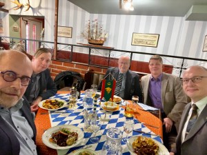 Helsingin Rajakillan 60-vuotisjuhlan osallistujia ravintolapöydässä, pöydän keskellä killan viiri.