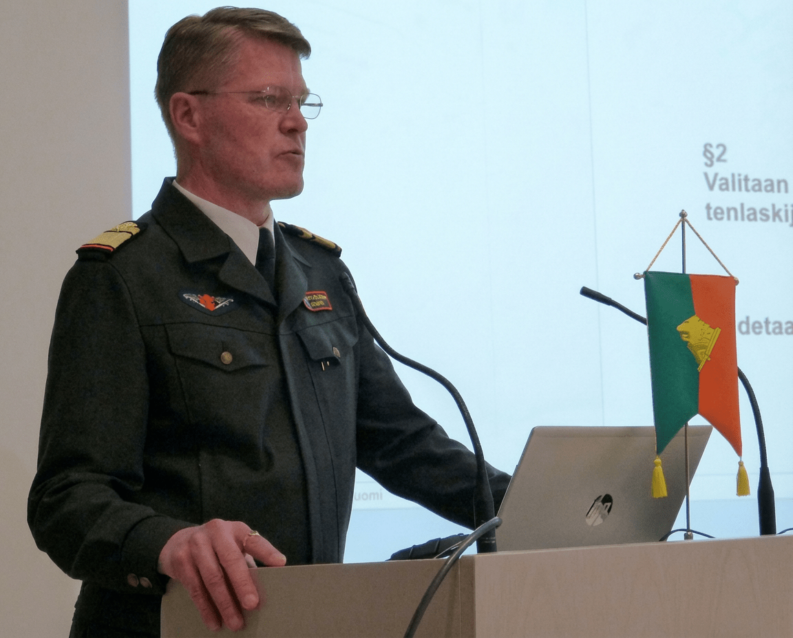 Puhuja pitää puheenvuoroa puhujakorokkeelta Rajan Perinneyhdistyksen vuosikokouksessa.